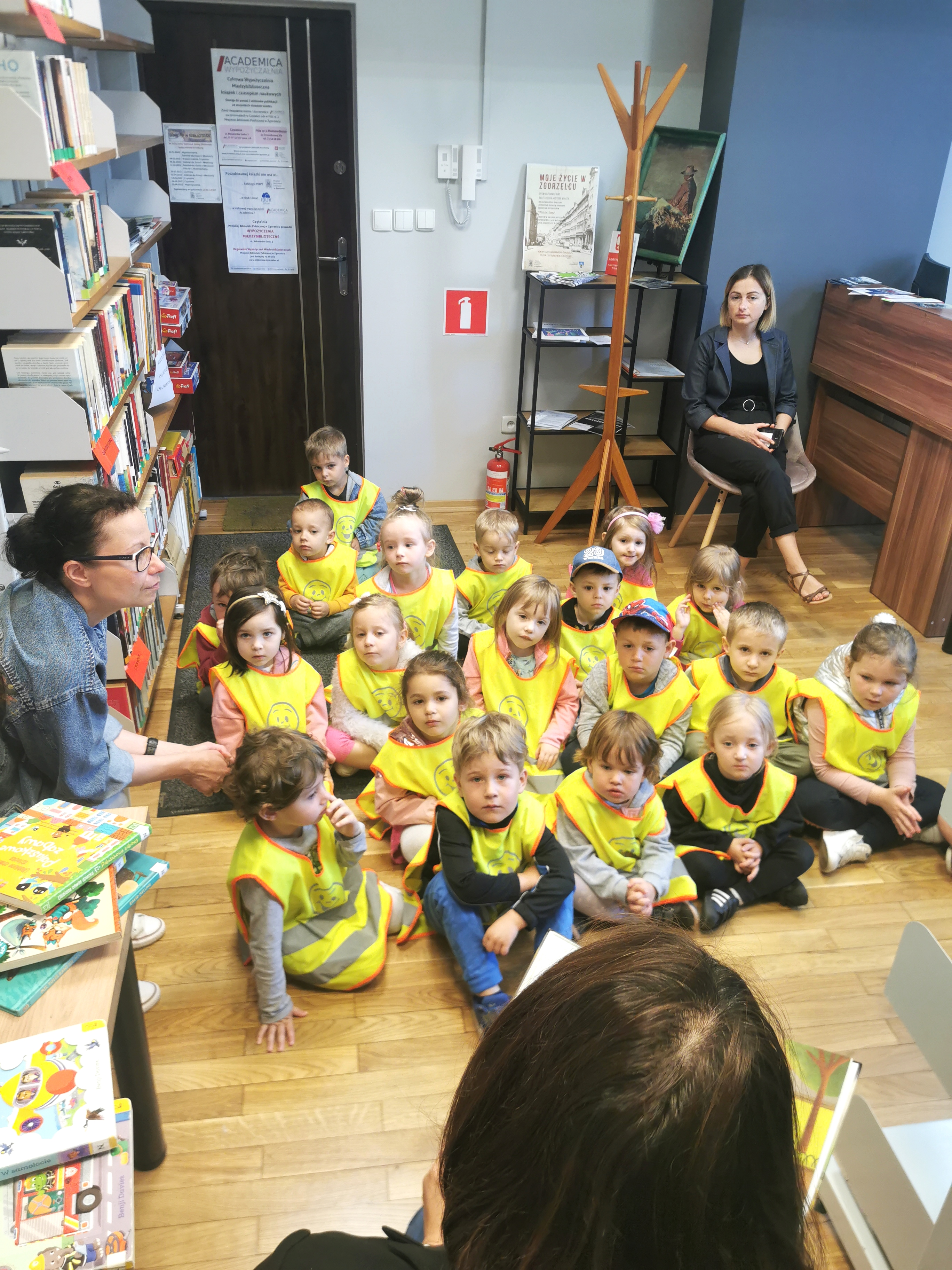 Grupa przedszkolaków słucha książki czytanej przez bibliotekarkę w pomieszczeniach Filii nr 3 MBP w Zgorzelcu.
