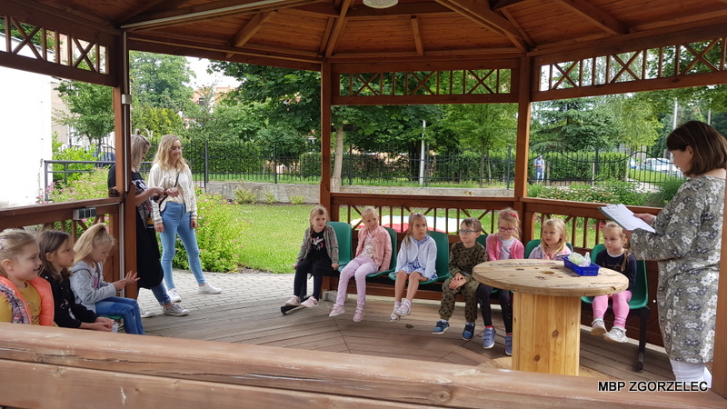 Dzieci z Przedszkola Mali Odkrywcy na placu przy Klubie Seniora w Zgorzelcu słuchają wiersza 