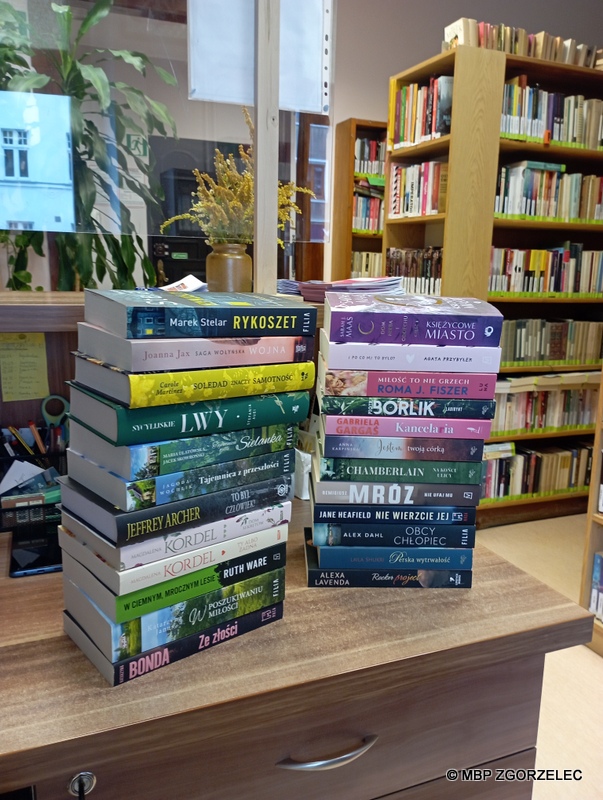 Grzbiety nowych książek w Wypożyczalni MBP. Zdjęcie jest jednocześnie odnośnikiem do wpisu "Sierpniowe nowości książkowe w Wypożyczalni".