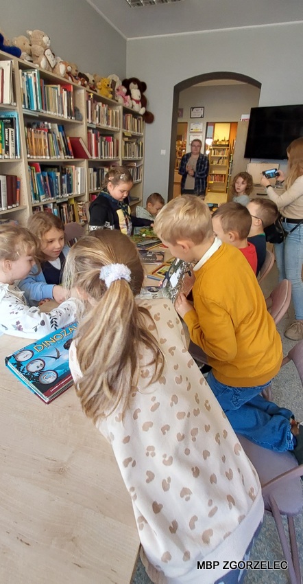 Uczniowie oglądają książki w czytelni Oddziału dla Dzieci i Młodzieży