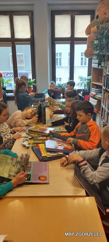 Dzieci ze Szkoły Podstawowej Cogito oglądają książki w czytelni Oddziału dla Dzieci i Młodzieży