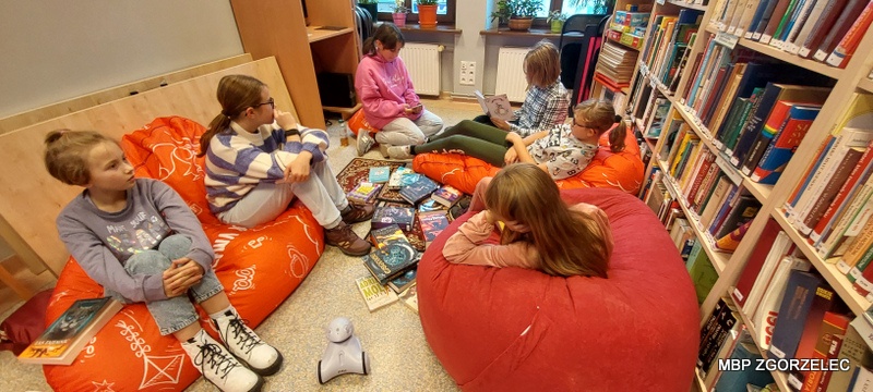 Klubowiczki w czytelni Oddziału dla Dzieci i Młodzieży słuchają wiersza o jesieni