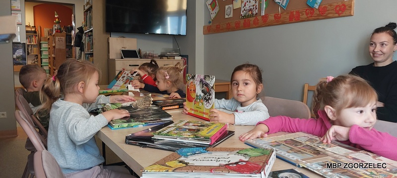 Dzieci w czytelni Oddziału dla dzieci i młodzieży przeglądają książki o zwierzętach