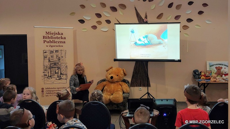 W pomieszczeniu Miejskiego Klubu Seniora w Zgorzelcu, Pani dyrektor Miejskiej Biblioteki Publicznej w Zgorzelcu - Krystyna Radzięta, czyta książkę o misiu w otoczeniu przedszkolaków.