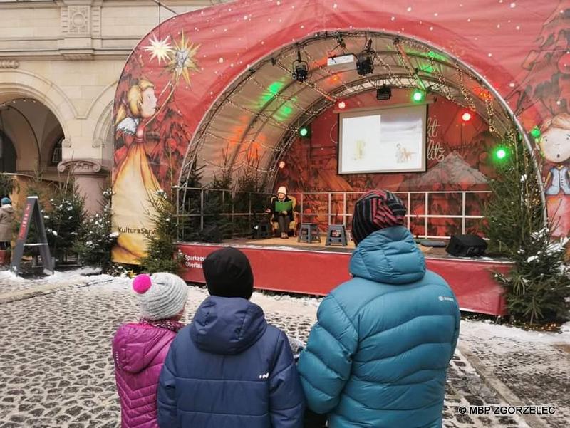 Bibliotekarka czyta świąteczne opowiadanie dla dzieci na Jarmarku Bożonarodzeniowym w Görlitz.
