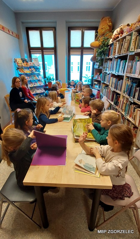 Przedszkolaki przeglądają książki w czytelni Oddziału dla Dzieci i Młodzieży