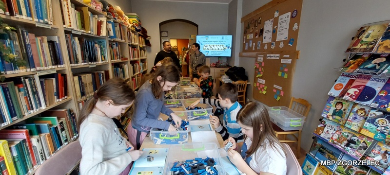 Uczestnicy warsztatów w czytelni Oddziału dla Dzieci i Młodzieży składają modele z klocków lego