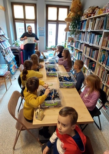 Uczestnicy warsztatów w czytelni Oddziału dla Dzieci i Młodzieży składają modele z klocków lego