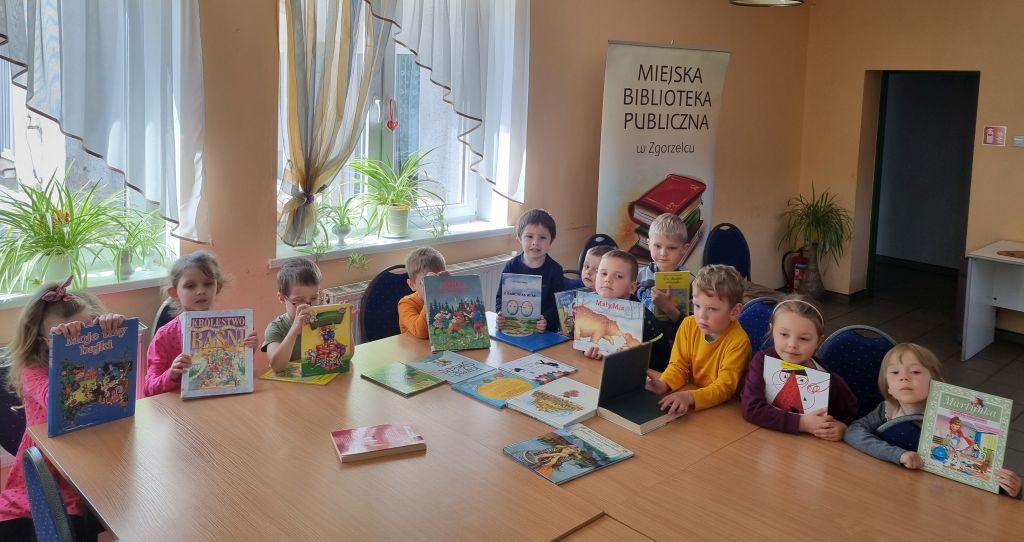 Dzieci przeglądają książki w bibliotece. Zdjęcie jest odnośnikiem do wpisu >"O rybaku i złotej rybce".