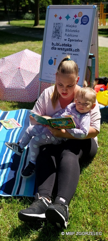 Na terenie otaczającym Fort Bolka i Lolka siedzi kobieta z dzieckiem i czyta książkę.