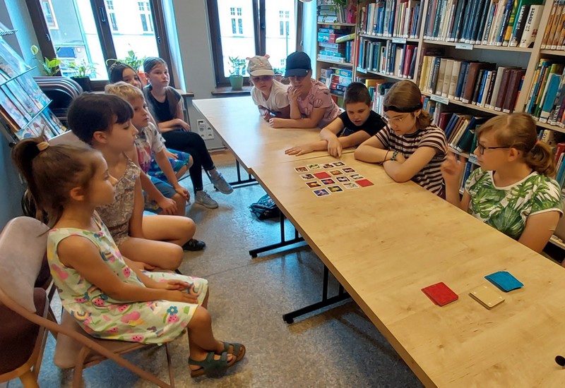 Dzieci drużynowo grają, podczas pierwszych zajęć w bibliotece