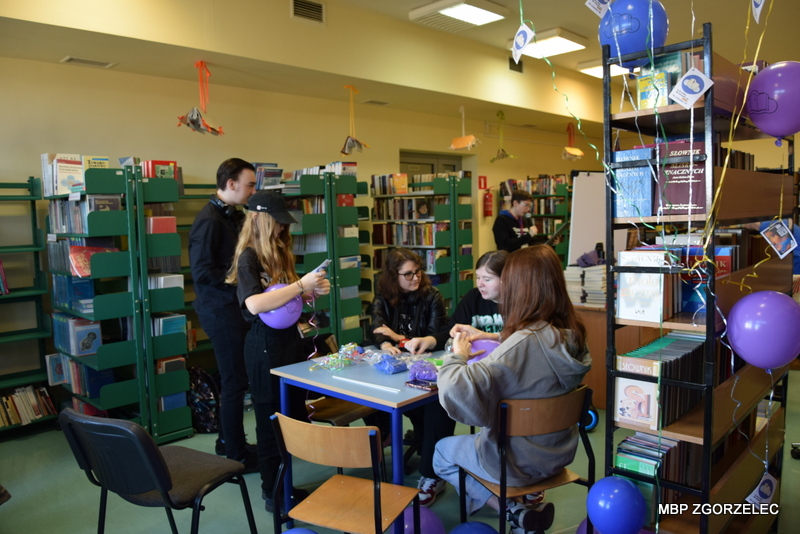 W pomieszczeniu biblioteki szkolnej, uczniowie przygotowują się do finału kampanii "Książki w chmurach"