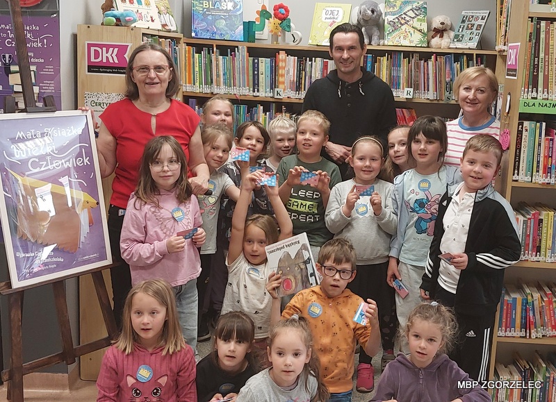 W pomieszczeniu Oddziału Dla Dzieci i Młodzieży MBP w Zgorzelcu grupa dzieci i wychowawców z Przedszkola Publicznego nr 2 w Zgorzelcu pozuje do wspólnego zdjęcia