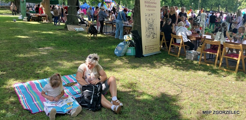Na skwerze przed Miejskim Domem Kultury w Zgorzelcu dzieci z rodzicami czytają książki