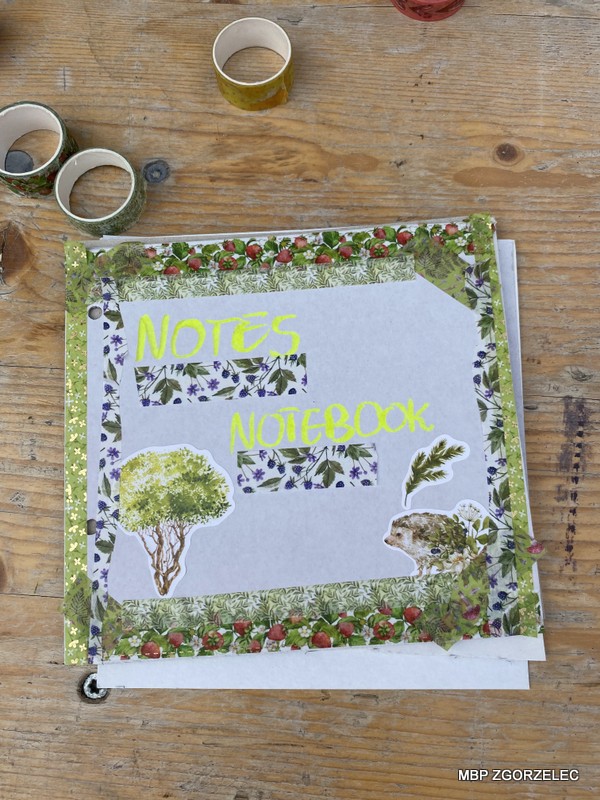 Ozdobiony zeszyt z napisem 'Notes Notebook' otoczony taśmami dekoracyjnymi.