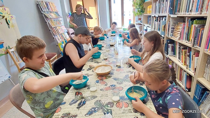 Dzieci mieszają składniki w miseczkach podczas zajęć w bibliotece.
