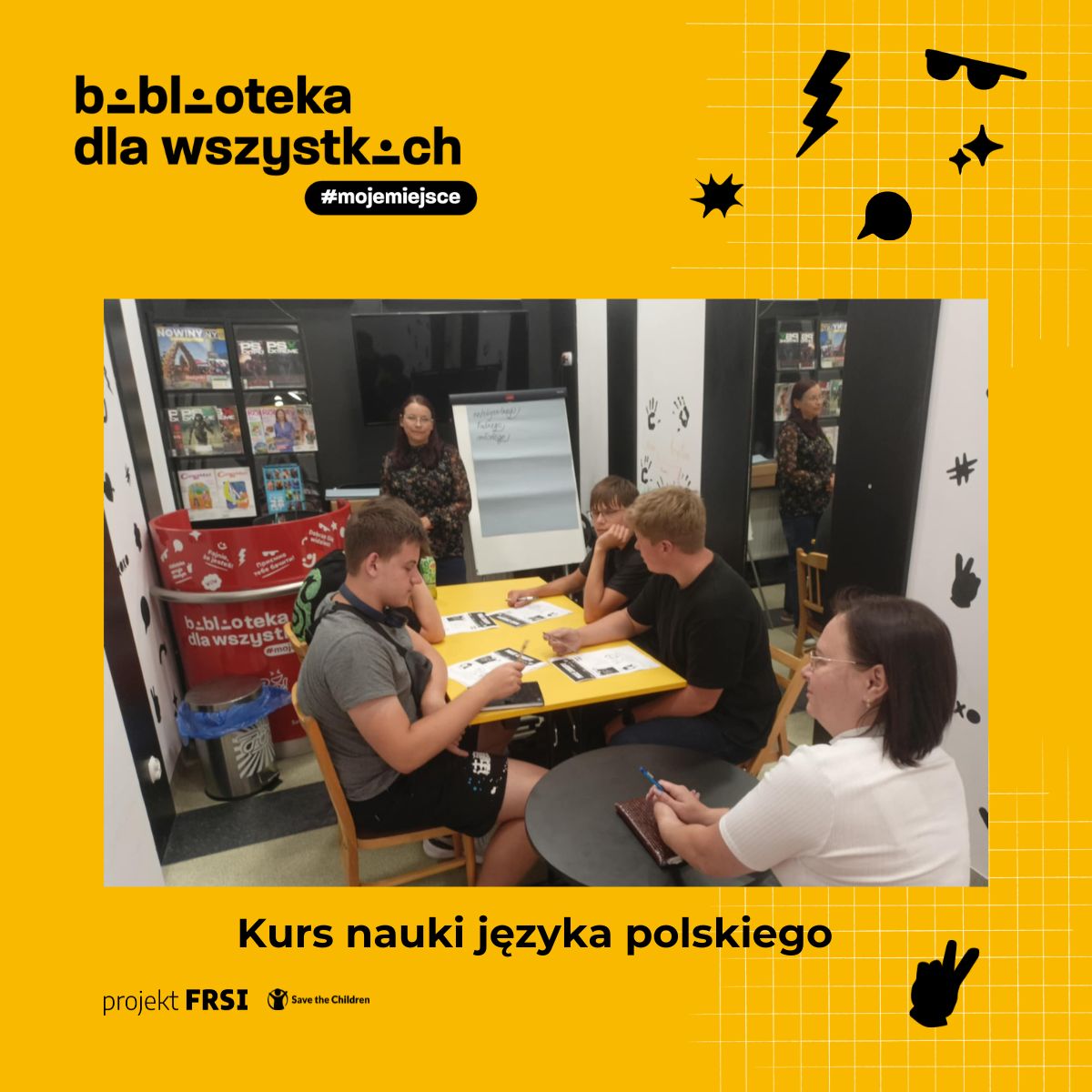 Uczestnicy kursu języka polskiego siedzą przy stole w bibliotece, otoczeni książkami i materiałami edukacyjnymi. Na zdjęciu znajduje się tekst: „biblioteka dla wszystkich #mojemiejsce, Kurs nauki języka polskiego, projekt FRSI Save the Children.