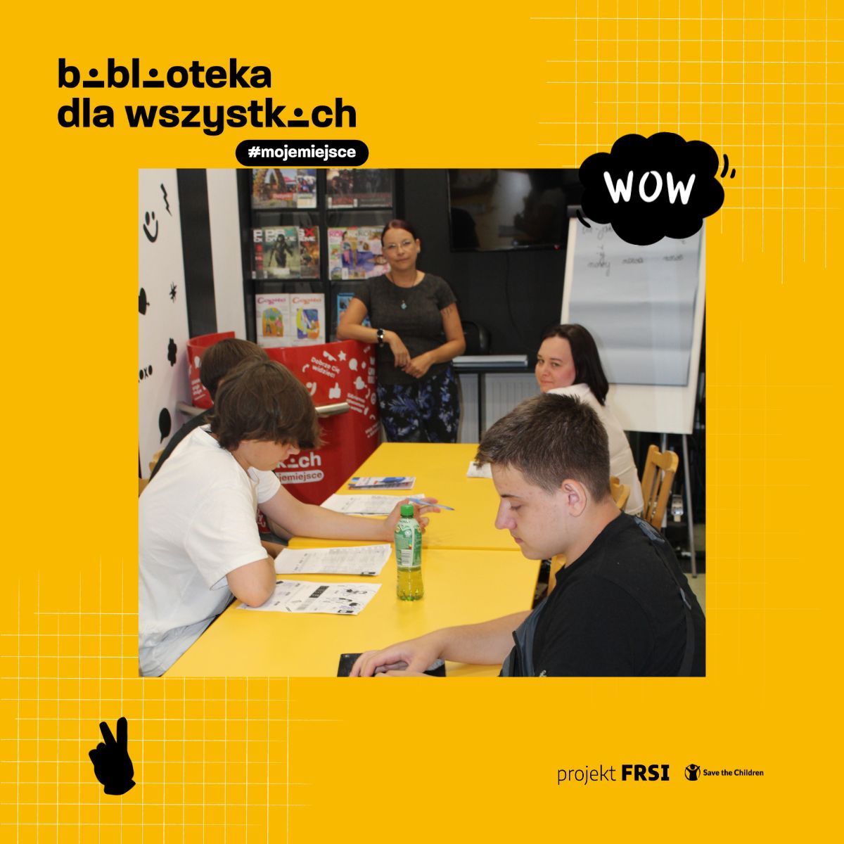 Uczestnicy kursu języka polskiego siedzą przy stole w bibliotece, otoczeni książkami i materiałami edukacyjnymi. Na zdjęciu znajduje się tekst: „biblioteka dla wszystkich #mojemiejsce, projekt FRSI Save the Children.