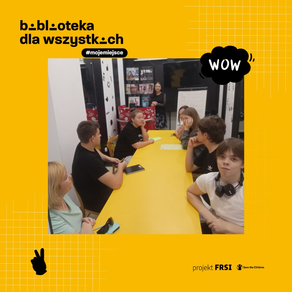 Uczestnicy kursu języka polskiego siedzą przy stole w bibliotece, otoczeni książkami i materiałami edukacyjnymi. Na zdjęciu znajduje się tekst: „biblioteka dla wszystkich #mojemiejsce, projekt FRSI Save the Children.