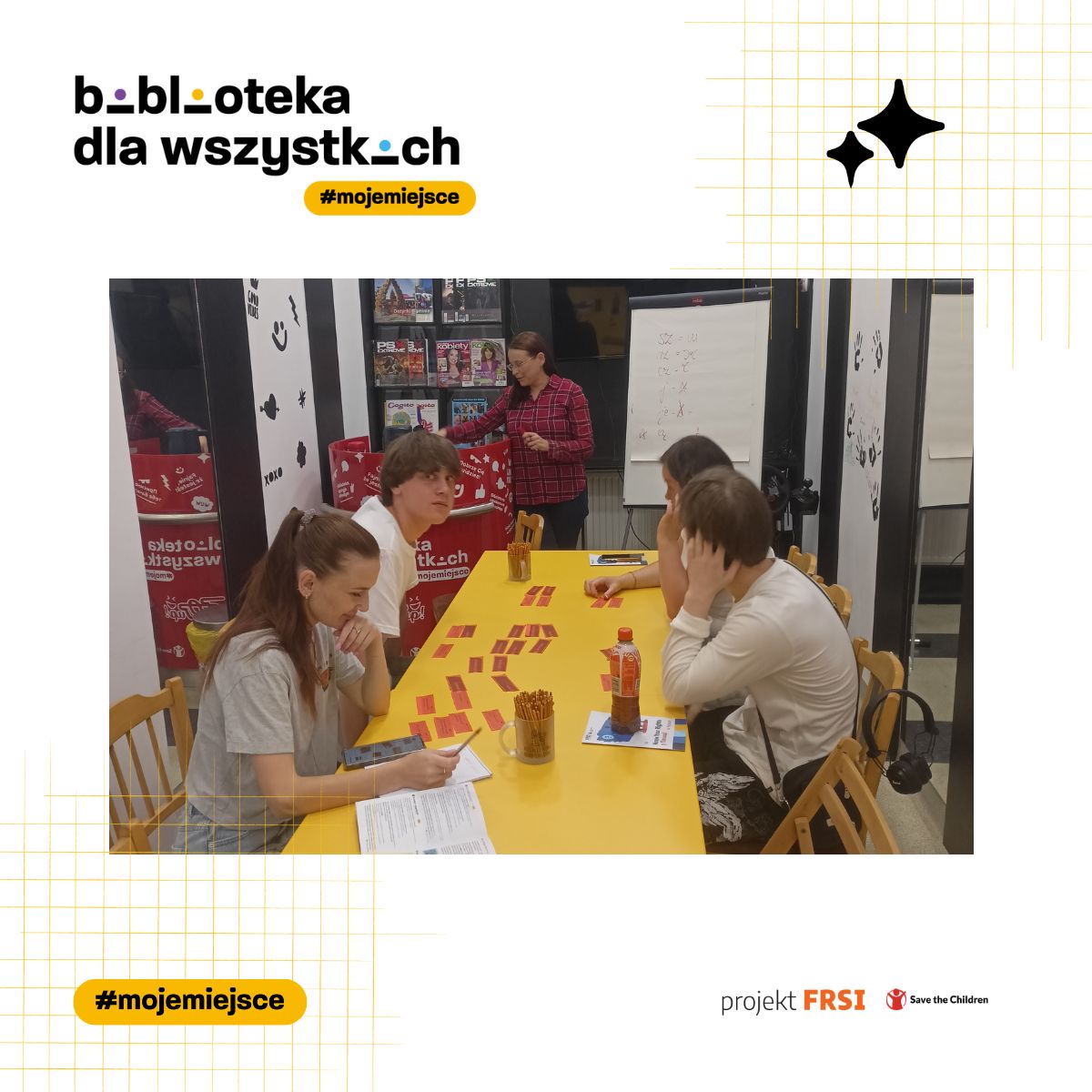 Uczestnicy kursu języka polskiego siedzą przy stole w bibliotece, otoczeni książkami i materiałami edukacyjnymi. Na zdjęciu znajduje się tekst: „biblioteka dla wszystkich #mojemiejsce, projekt FRSI Save the Children.