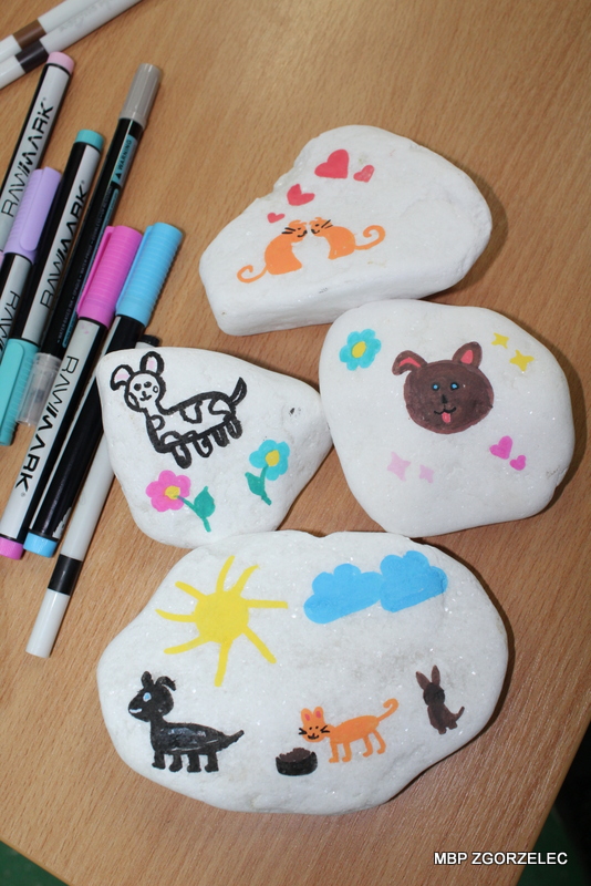 Malowanie kamieni z motywami zwierząt i książek. Obok leżą markery.