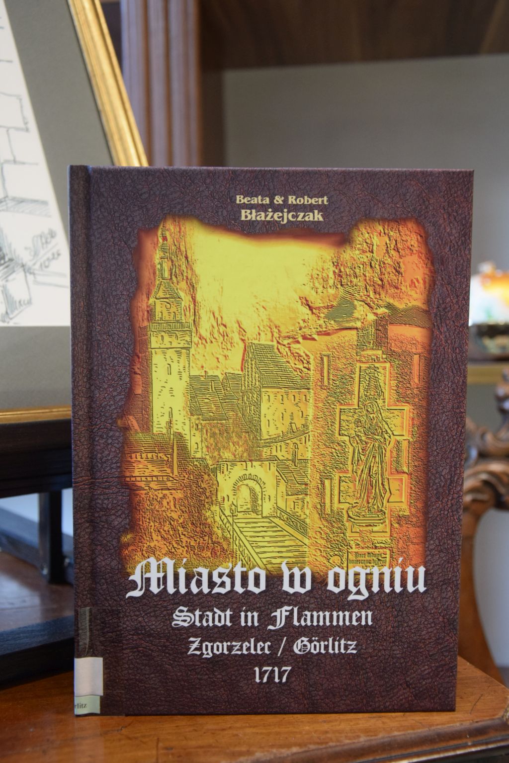 Okładka książki Beaty i Roberta Błażejczak pt. „Miasto w ogniu. Zgorzelec / Görlitz 1717” wydanej przez Wydawnictwo Poligrafia AD REM. Zdjęcie jest odnośnikiem do wpisu o publikacji.