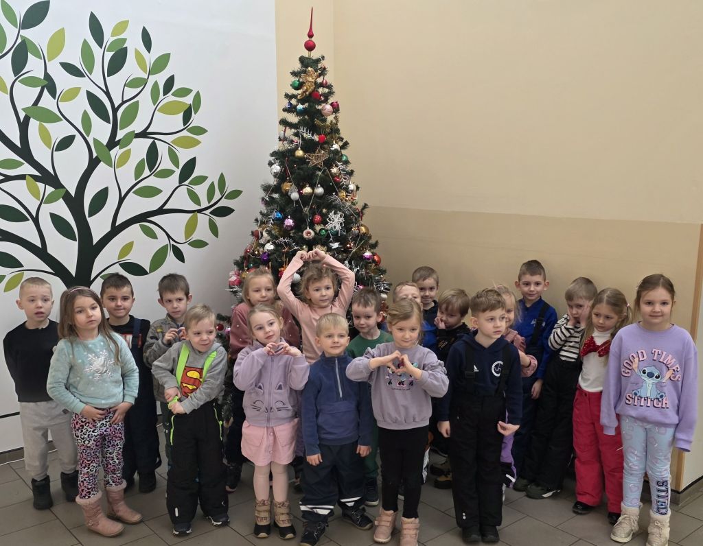 Grupa przedszkolaków pozuje do zdjęcia przy choince podczas spotkania w&nbsp;bibliotece.