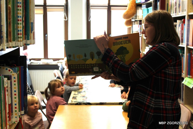 Podczas głośnego czytania dzieci słuchają fragmentów książki „Podróż Pana Brokuła” prezentowanej w&nbsp;Oddziale dla Dzieci i&nbsp;Młodzieży.